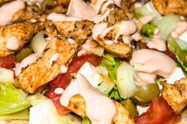 Kebab salad with grilled meat and vegetables topped with sauce, macro close-up