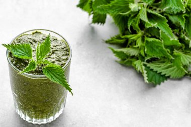 Beyaz arka planda yeşil ısırgan otu yapraklı sağlıklı bir smoothie.