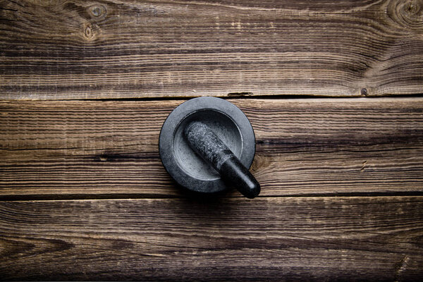 Черный раствор с пестиком на деревянном столе, вид сверху
