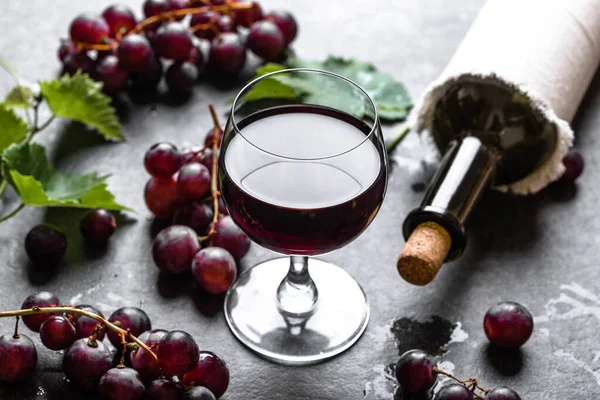 Vidro de vinho com uvas vermelhas e garrafa de vinho com cortiça — Fotografia de Stock