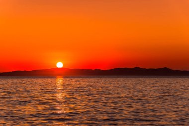 Gün batımının deniz ve dağların üzerinde olduğu güzel turuncu gökyüzü, Zadar, Dalmaçya, Hırvatistan