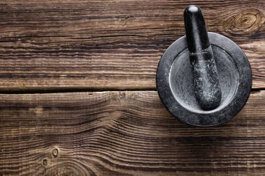 Pestle ve havan topu. Tahta masanın üzerinde siyah taş var.