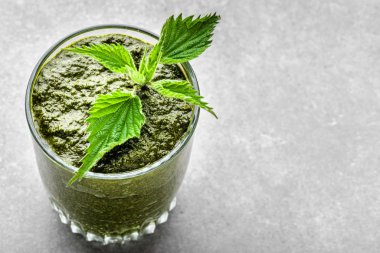 Beyaz arka planda yeşil ısırgan otu yapraklı sağlıklı bir smoothie.