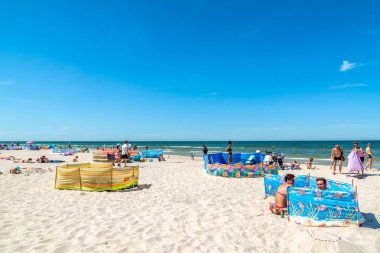 LEBA, POLAND - 09 HAZİRAN 2019 Kumda, denizde, yaz tatilinde insanları güneşlendirmek