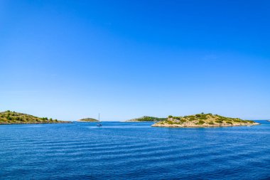 Adriyatik kıyıları kayalık plajlar, küçük adalar, mavi denizde tekneler ve yelkenli yatlar, Hırvatistan, Dalmaçya