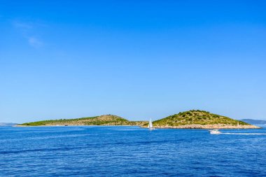 Adriyatik kıyıları kayalık plajlar, küçük adalar, mavi denizde tekneler ve yelkenli yatlar, Hırvatistan, Dalmaçya