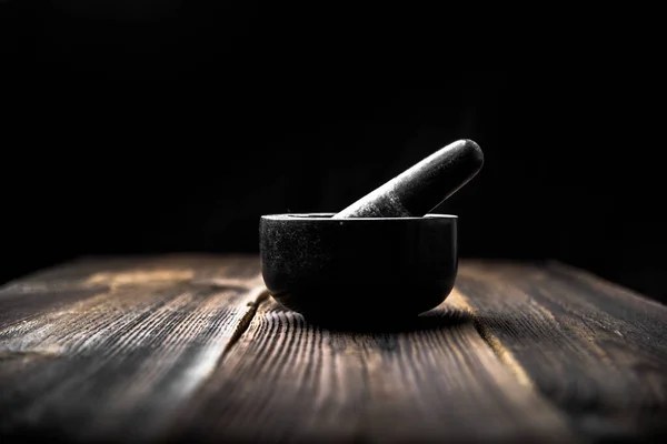 Black mortar with pestle on wooden table