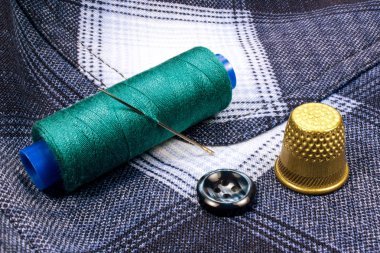 Yeşil iş parçacığı üzerinde yüksük ve bir düğme gömlek arka plan üzerinde plastik bir biriktirme