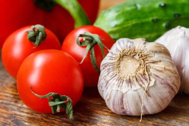 Kiraz domates, sarımsak ampul, tatlı biber ve salatalık eski bir ahşap tablo