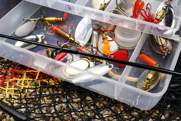 Caja de almacenamiento abierta con accesorios para la pesca y cebos de pesca en el suelo pedregoso — Foto de Stock