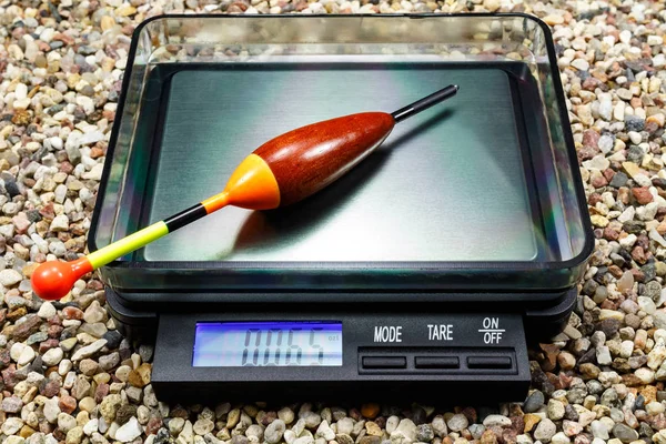 Weighting a wooden fishing float on a pocket scale — Stock Photo, Image