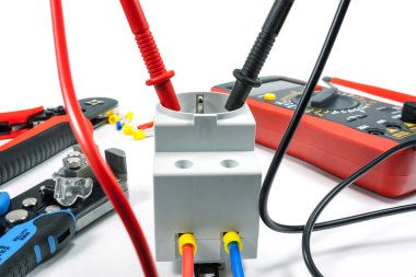 Beyaz zemin üzerinde bir multimetre ile elektrik prizine gerilim ölçümü
