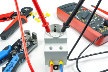 Beyaz zemin üzerinde bir multimetre ile elektrik prizine gerilim ölçümü