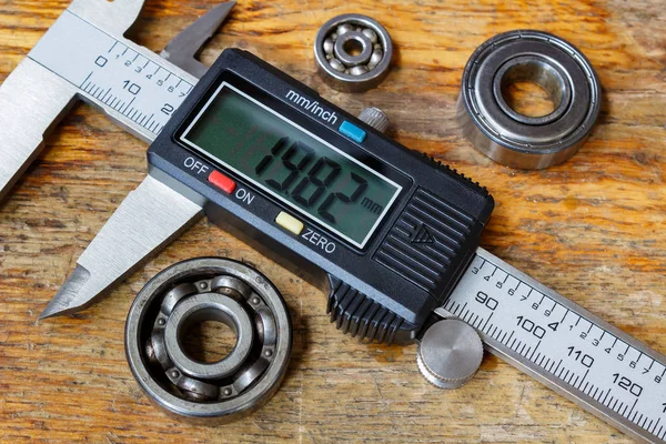 Electronic caliper with ball bearings on a wooden table in the workshop — Stock Photo, Image