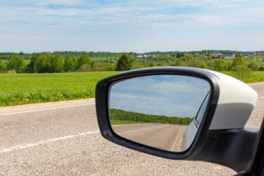 Yol güneşli bir günde araba yan aynaya yansıyan. Seyahat kavramı