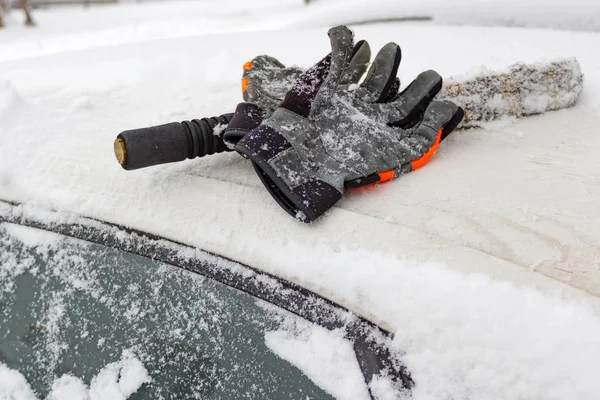 Rękawiczki zimowe i śnieg pędzlem na dachu samochodu pokryte śniegiem — Zdjęcie stockowe