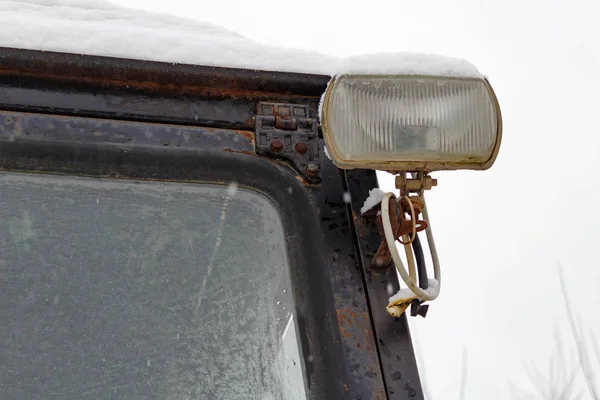 Old tractor secondary headlight closeup covered with snow — Stock Photo, Image