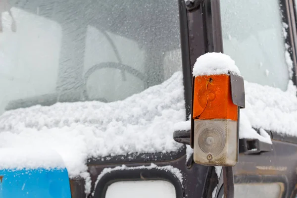 Parkering och blinkers ljus är täckt med snö på en gammal traktor-närbild — Stockfoto