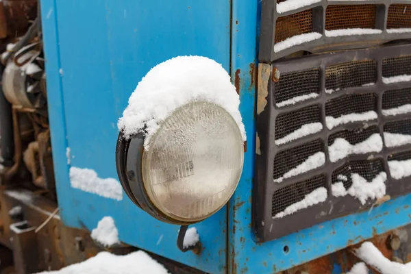 Gammal traktor huvudsakliga strålkastare närbild täckt med snö — Stockfoto