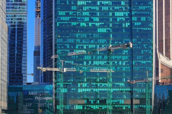俄罗斯莫斯科-2018年4月14日: 在阳光明媚的日子里摩天大楼玻璃幕墙背景下的建筑起重机 — 图库照片