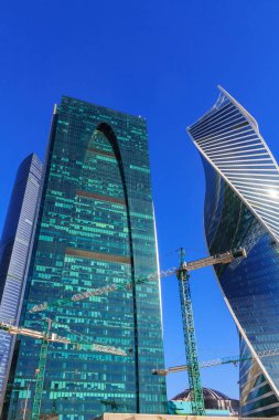 Güneşli bir gün içinde gökdelenler cam cephe arka plan üzerinde inşaat vinçleri
