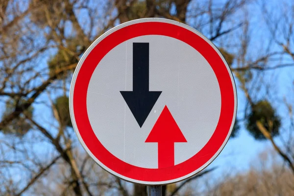 Verkeersbord voordeel van tegenliggers tegen een achtergrond van bomen en de blauwe hemel — Stockfoto