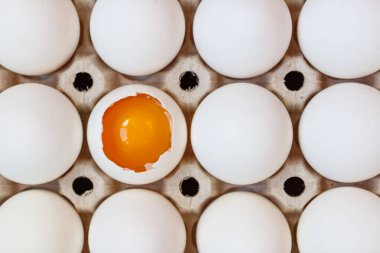 Tavuk yumurta sarısı bütün yumurta karton tepsi closeup arasında açıldı. Üstten Görünüm