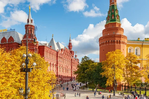 Moskova, Rusya - 08 Ekim 2019: Güneşli sonbahar gününde Moskova Kremlin ve Devlet Tarih Müzesi binaları arasında Kızıl Meydan 'a giden taştan yolda yürüyen turistler. Manezhnaya meydanından görüntü
