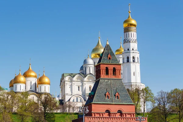 Moscú, Rusia - 01 de mayo de 2019: Iglesias del Kremlin de Moscú en la colina verde contra la torre a la luz del sol en la mañana de primavera — Foto de Stock