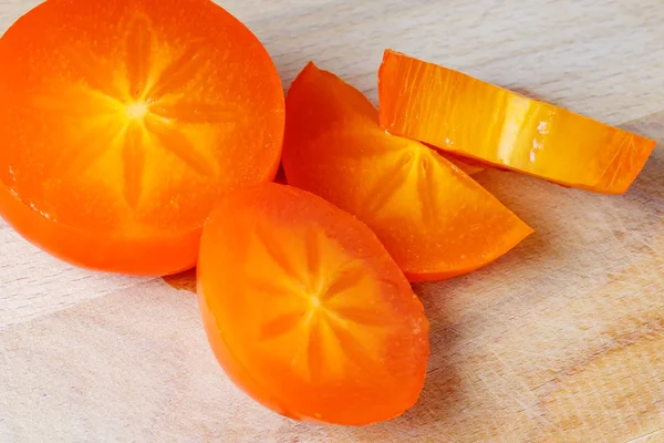 Tranches de kaki juteux orange vif sur la planche à découper en bois close-up — Photo