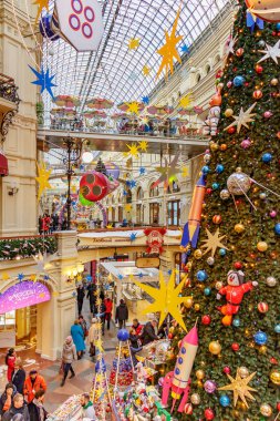 Moskova, Rusya - 21 Kasım 2019: Kızıl Meydan 'daki Sakız' da Yeni Yıl. Moskova 'daki Sakız Devlet Mağazası' nın merkezindeki süslü Noel ağacının yakınındaki insanlar.