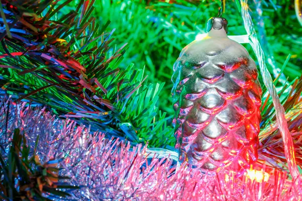 Skleněný vánoční kornout na větev dekorativní jedle zblízka ve světle barevných světel elektrického girlandu — Stock fotografie