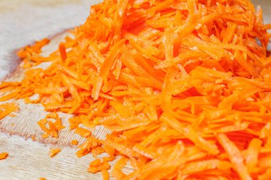 Eski ahşap kesme tahtasının üstünde taze, sulu rendelenmiş havuç.