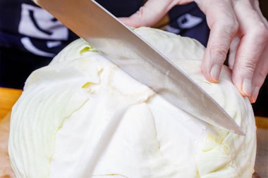 Yakından kesmeden önce taze beyaz lahananın tepesinde şef bıçağı olan kadın eller.