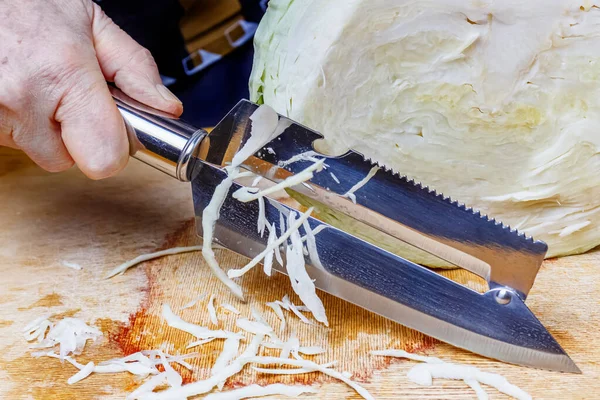 Жіноча рука з ножем для подрібнення капусти та голови свіжої білої капусти на дерев'яній обробній дошці — стокове фото