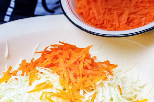Fresh juicy grated carrot on chopped white cabbage in the metal bowl — Stock Photo, Image