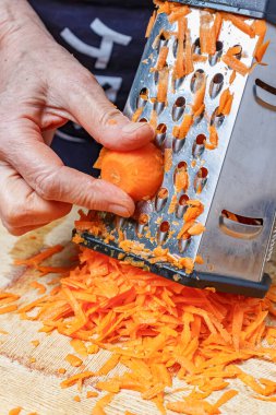 Paslanmaz çelik rendesinin üzerinde taze, sulu havuç rendeliyorum.