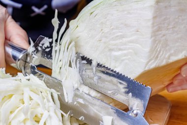 Lahana öğütmek için paslanmaz çelik bıçakla taze, sulu beyaz lahanayı öğütüyorum.