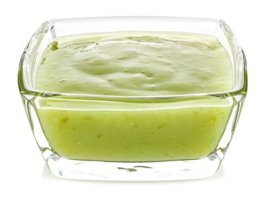 Yeşil biber sosu, beyaz arka planda izole edilmiş küçük şeffaf cam bir kasede limon.