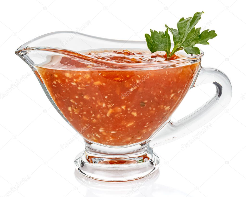 Hot tomato sauce with parsley leaves in a transparent glass gravy boat isolated on white background
