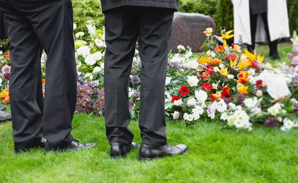 Zwei Männer bewässern Beerdigungsblumen lizenzfreie Stockbilder