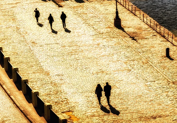 Silhuettes pejalan kaki berjalan di sore hari hangat cahaya — Stok Foto