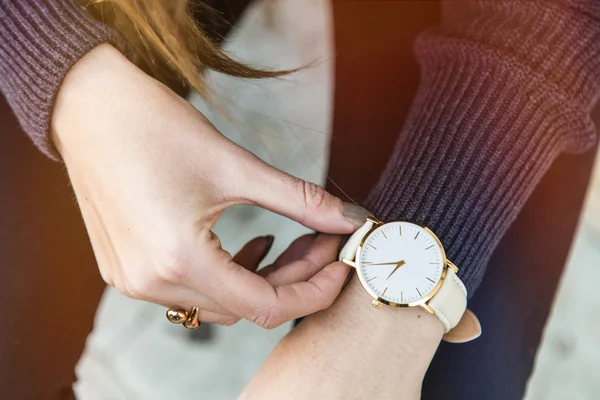 Close up detalhes da moda, jovem mulher de negócios segurando seu relógio de ouro. classificado em cores quentes . — Fotografia de Stock