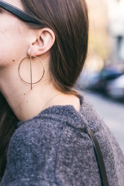 Ayrıntılar bir moda sonbahar kıyafeti. gri kazak ve güzel altın küpe giyen genç kadın