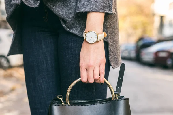 Cerrar los detalles de moda, joven mujer de negocios sosteniendo su bolso. vistiendo joyas de oro, y reloj blanco . — Foto de Stock