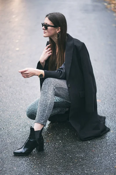 Фешенебельная женщина в черном широком пальто и блестящих брюках. детали идеального осеннего наряда моды. детали костюма блогера моды . Лицензионные Стоковые Фото
