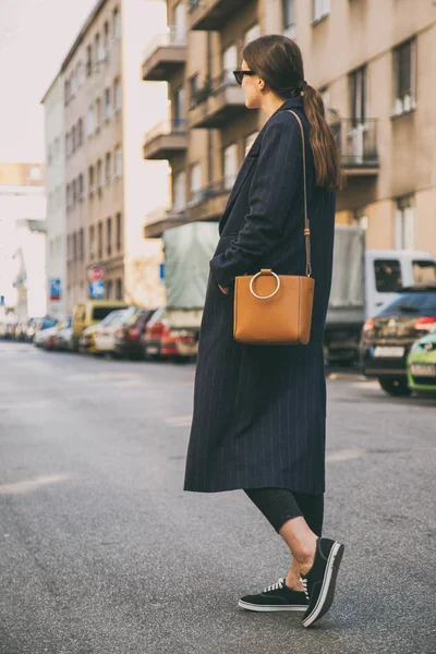 Donna alla moda indossa un cappotto oversize blu navy e una borsa alla moda marrone. perfetto vestito di moda primavera . — Foto Stock