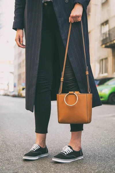 Detalles de ropa de blogger de moda. mujer de moda con un abrigo azul de gran tamaño, vaqueros negros, zapatillas negras un bolso de moda marrón. detalle de un perfecto atuendo de moda de primavera . —  Fotos de Stock