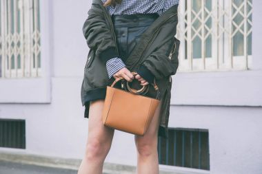 moda detayları, kahverengi zarif çantasını tutan kadın kapatın. Pötikareli onay üst ve bir bombardıman ceket poz ideal bahar kıyafet accessories.fashion blogger.