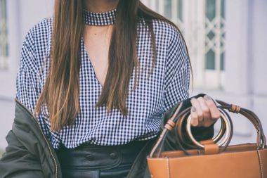 moda detayları, kahverengi zarif çantasını tutan kadın kapatın. Pötikareli onay üst ve bir bombardıman ceket poz ideal bahar kıyafet accessories.fashion blogger.